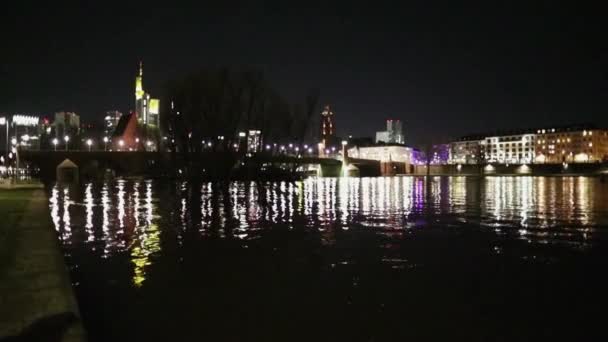 Bright lighting of the night city is reflected in the black water of the river — Stock Video