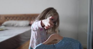 Pijamalı güzel sarışın bir sabah elbisesi seçiyor ve seviniyor. 