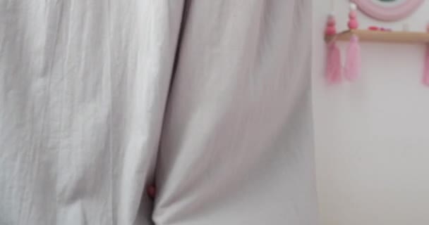 Linda menina loira se esconde atrás de cortinas cinza em casa — Vídeo de Stock
