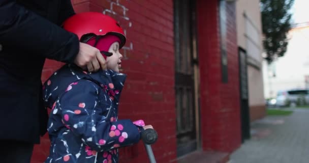 A little girl wears a bicycle helmet on her head before walking — Stock Video