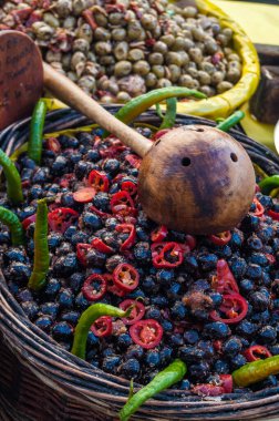 Fransız pazarında siyah ve yeşil zeytinli otlar ve ahşap kaşıklar.