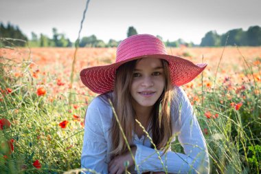 Haşhaş fiyortunda oturan genç bir kadın, kırmızı bando şapkalı, rahatlatıcı, Fransa provence.