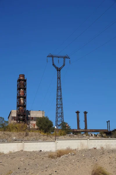Fabrika bölgeyle bir boru ve bir güç hattı direği — Stok fotoğraf