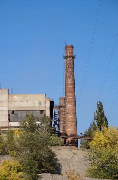 Fabrika bölgeyle bir boru ve bir güç hattı direği — Stok fotoğraf