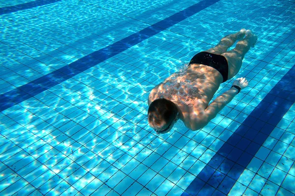 Svømmer i swimmingpoolen - Stock-foto