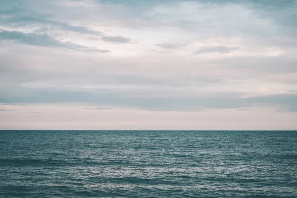 Paisaje de playa y el horizonte con atardecer nublado