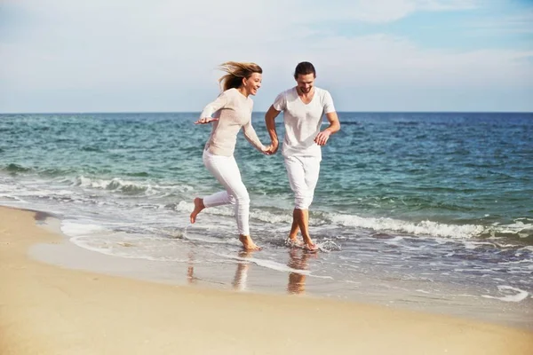 Jovem casal bonito correndo e passando um bom tempo na praia de férias . — Fotografia de Stock