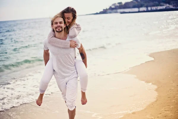 Joven hermosa pareja de vacaciones. La chica saltó sobre el tipo desde arriba. Amor para siempre. Divertirse . — Foto de Stock