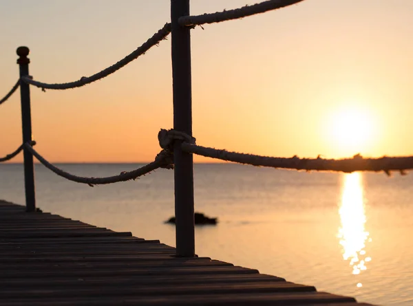 Un ponte di legno sopra il mare al tramonto — Foto Stock