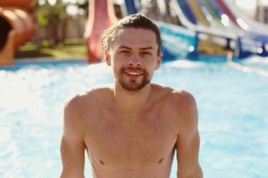 yakışıklı bir delikanlı bir aquapark içinde oturan ve gülümseyen