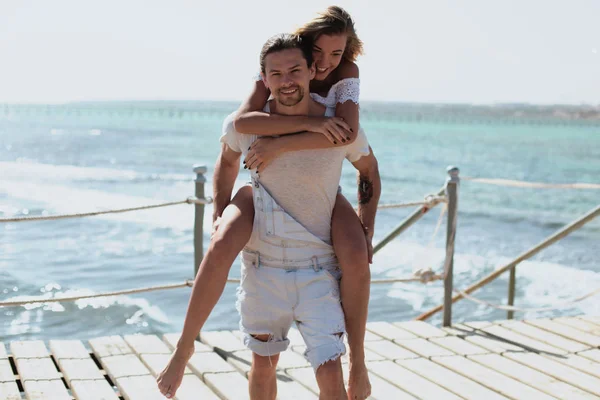 Una hermosa pareja joven en el puente de madera cerca del mar — Foto de Stock