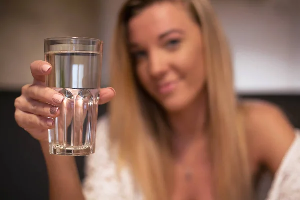 Un vaso de agua mineral clara en manos de una joven y hermosa mujer sentada en un café —  Fotos de Stock