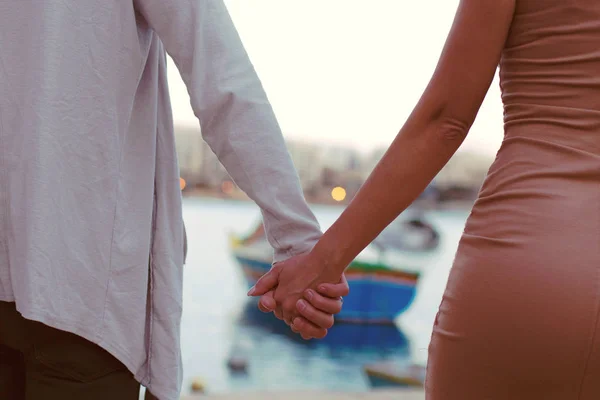 Primer plano de pareja joven cogida de la mano mientras camina de vacaciones, aislada cerca del mar — Foto de Stock