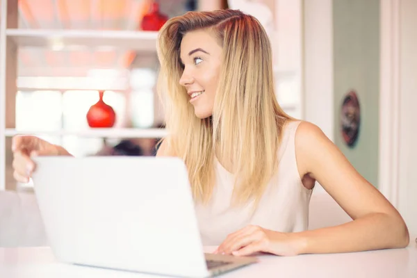 Vackra glada unga leende affärskvinna tittar på någon som arbetar på en bärbar dator i ett mysigt café på morgonen — Stockfoto