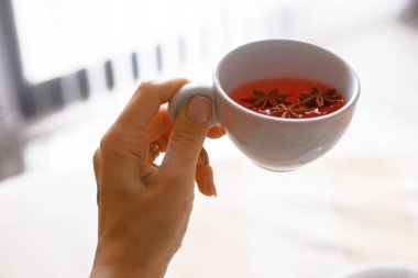 Bir kız bir fincan getiriyor sabah çay, bir bardak çay ile el