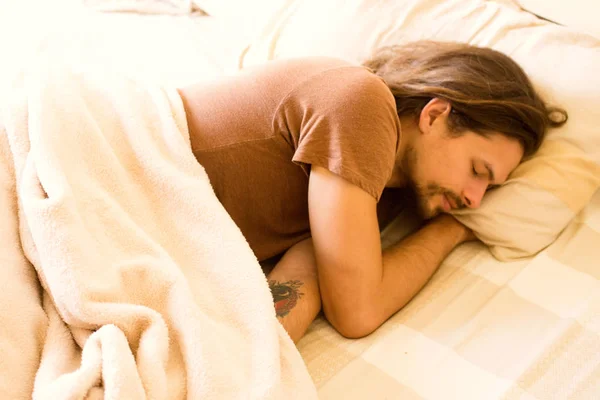 Ένας όμορφος νεαρός άνδρας κοιμάται στο κρεβάτι νωρίς το πρωί απολαμβάνοντας το όνειρό του — Φωτογραφία Αρχείου