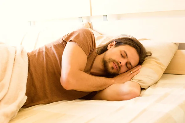 Ένας όμορφος νεαρός άνδρας κοιμάται στο κρεβάτι νωρίς το πρωί απολαμβάνοντας το όνειρό του — Φωτογραφία Αρχείου