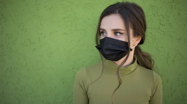 Piękna dziewczyna na zielonym tle z maską przeciw grypie. Chronione i oszczędzone przed problemami z oddychaniem. Obraz Stockowy