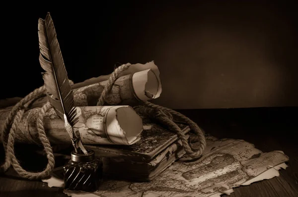 Quill pen, inkwell and old rolled up maps and papers, sepia effect