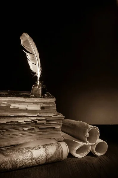 Quill pen, inkwell and old rolled up maps and papers, sepia effect