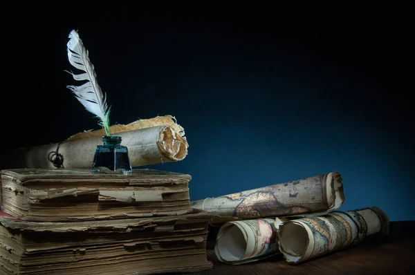 Quill pen, inkwell, old rolled up maps and papers on a dark background