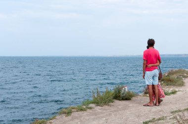 Deniz kıyısında sevgi dolu bir çift Uzağa bakar.