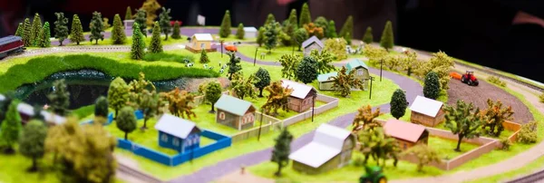 Minyatür köy. İnekler göl kenarında köydeki evlerin arasında otlarlar..