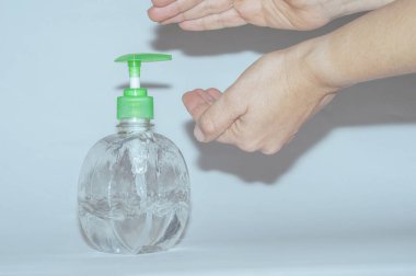 Covid19 Coronavirus gibi virüslerin yol açtığı hastalıkları önlemek için önlem olarak antibakteriyel jel kullanan eller. Bogota Kolombiya 'da ışık ve mavi arka planda el temizliği. Botella de Jabn antibakteriyel para la limpieza de las manos.