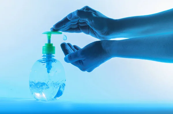 Hands applying antibacterial gel as a measure to prevent diseases caused by viruses such as the covid19 coronavirus. Hand hygiene on light and blue background in Bogota Colombia. Botella de jabn antibacterial para la limpieza de las manos.