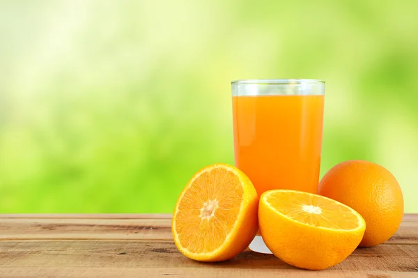 Portakal suyu ve portakal ahşap masa üzerinde arka plan bulanıklık.