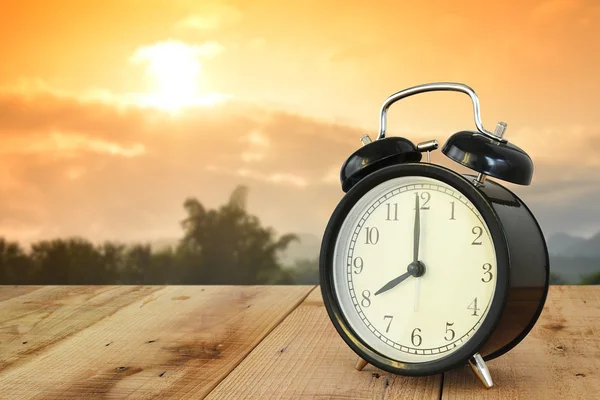 Çalar saat ahşap ve güzel gündoğumu arka plan üzerinde.