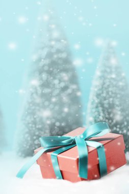 Noel kırmızı hediye kutusu ve bulanık Noel ağaçları..