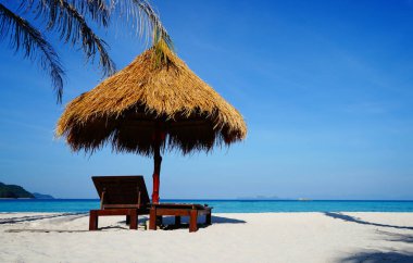 Yaz tatilinde kumsalda sandalye ve şemsiye..