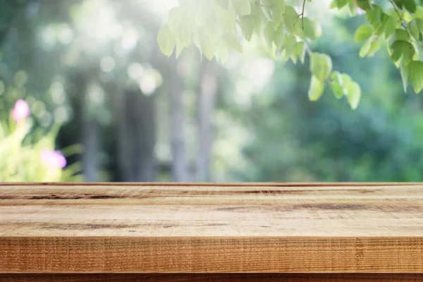 木製の机とぼやけた庭の緑の自然背景 — ストック写真