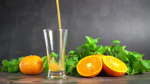 将新鲜的橙汁倒入一杯中 桌上放有橙子 水果和薄荷糖 健康食品 — 图库视频影像