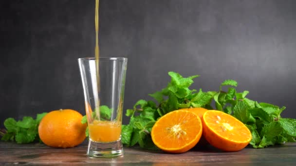 新鮮なオレンジジュースをテーブルの上にオレンジフルーツとペパーミントとガラスに入れ 健康的な食べ物 スローモーション — ストック動画