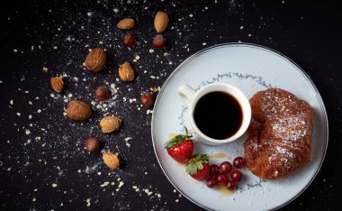 Mor arka planda fındıklı beyaz bir tabakta gevrek kahverengi kruvasan manzarası..