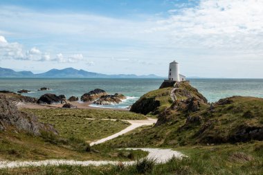 Anglesey, Galler 'deki Ynys Llanddwyn' deki Tr Mawr deniz feneri Menai Boğazı 'nın batı girişini gösteriyor..