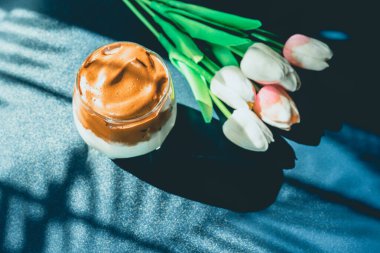 Flay, dalgona 'dan ya da köpüklü kahveyi sevmişti. Klasik mavi ve palmiye ağacının gölgesi ve lale arka planında.