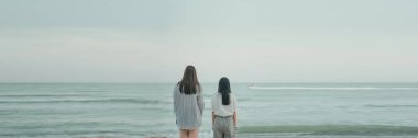 Yaz tatilinde iki kadın yolcunun arkasında durup plajı seyretmek.