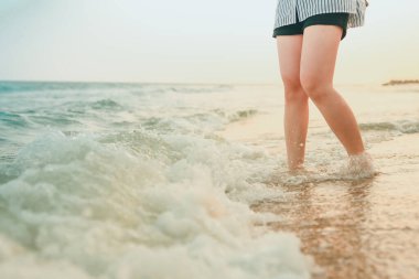 Yaz mevsiminde yumuşak odaklı plaj geçmişi olan kumsaldaki kadın bacağı