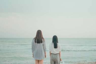 Yaz tatilinde iki kadın yolcunun arkasında durup plajı seyretmek.