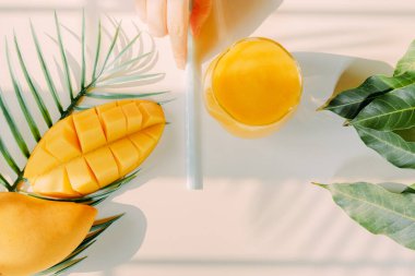Üst ve düz yaz meyveleri güzellik kadının elinden tut mango suyu ve beyaz izole arkaplan ile mango dilimi yemek için çatal kullan
