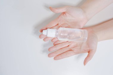 COVID-19 virüs aktivitesini beyaz izole edilmiş arka planda alkol jeli kullanırken üst görüşlü kadın elinden temizleyin ve koruyun