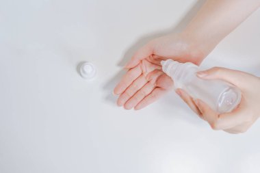 COVID-19 virüs aktivitesini beyaz izole edilmiş arka planda alkol jeli kullanırken üst görüşlü kadın elinden temizleyin ve koruyun