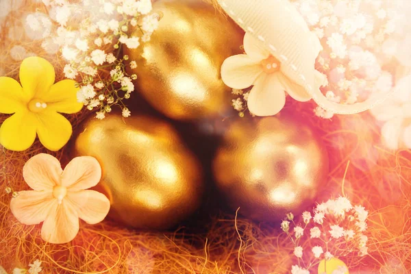 Złote jaja wielkanocne z kwiatami w gniazdo — Zdjęcie stockowe