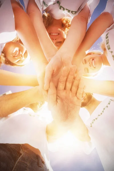 Vrijwilligers met handen samen tegen blauwe hemel — Stockfoto