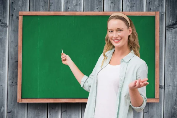 Vrouwelijke student permanent tegen schoolbord — Stockfoto