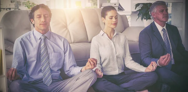 Business people meditating in lotus pose — Stock Photo, Image