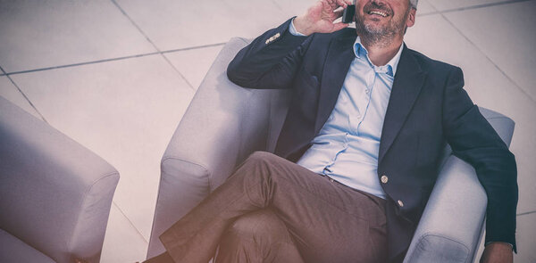 Businessman sitting on a chair and talking on mobile phone